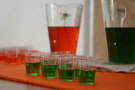 Kleine Gläser mit grüner Flüssigkeit im Hintergrund Karaffen