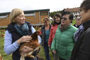 Von Besucherinnen umringte Frau hält Huhn im Arm 
