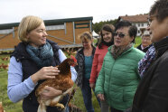 Von Besucherinnen umringte Frau hält Huhn im Arm