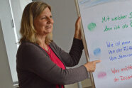 Frau zeigt auf Text auf einer Flip-Chart