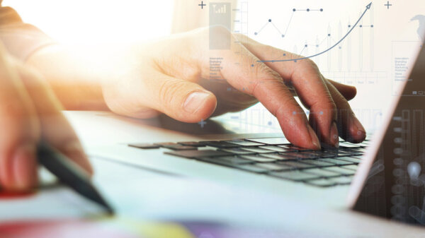 Hand arbeitet an einem Computer mit Diagrammen