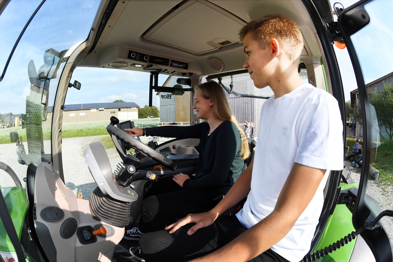 Zwei Schüler sitzen auf einem Traktor