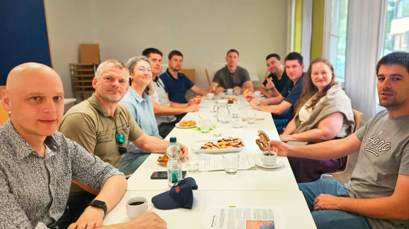 Mehrere Personen sitzen um einen großen weißen Tisch